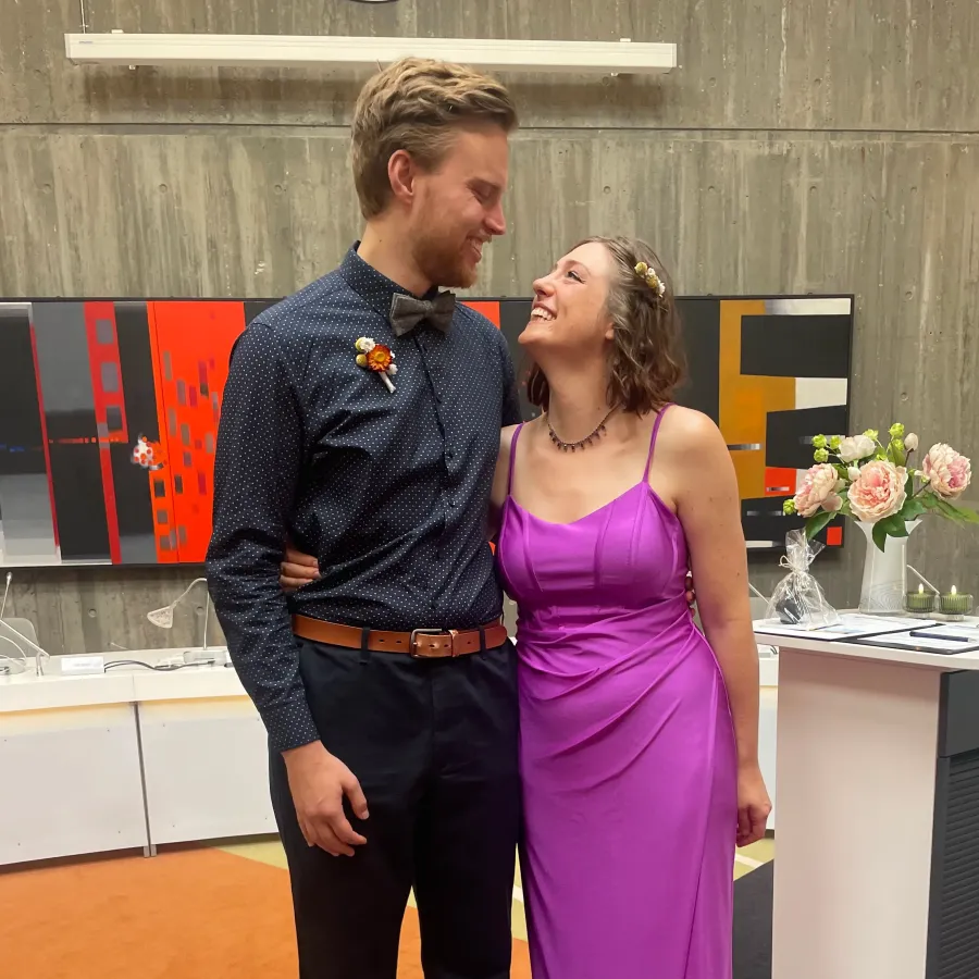 Teresa und Markus in Hochzeitskleidung, sie sehen sich lachend an